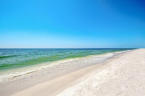 A beach with clear water and a sandy shore. - Ground floor, Gulf front condo with pools, hot tubs, tennis courts, and gym (Orange Beach)