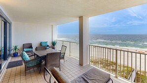 Ein Balkon mit Blick auf das Meer, Korbmöbel und Blumentöpfen.