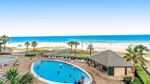 Ein Poolbereich mit Liegestühlen und Blick auf den Strand.
