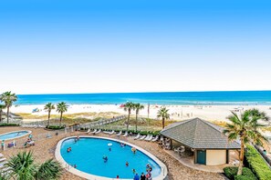 A pool area with lounge chairs and a beach view. - Gulf front condo w unobstructed beach views - shared pools, hot tub, & tennis (Orange Beach)