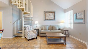 A living room with a staircase, a sofa, a coffee table, and a lamp. - Spacious condo near the beach with great view, bonus loft, and shared pool (Orange Beach)