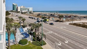 A multi-level hotel with a swimming pool, a parking lot, and a view of the beach and ocean. - Spacious condo near the beach with great view, bonus loft, and shared pool (Orange Beach)