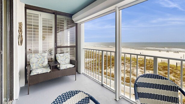 A balcony with a view of the beach, wicker furniture, and a railing. - Waterfront condo w/ a private balcony, community pools, & fitness center (Orange Beach)