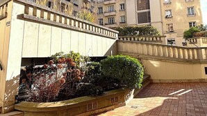 Un edificio residenziale a più piani con balconi, un cortile centrale con piante e un vialetto in mattoni.