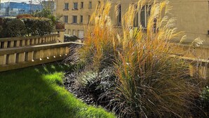 Un edificio residenziale a più piani con balconi, un'area giardino con erba e arbusti, e un cielo sereno con nuvole.