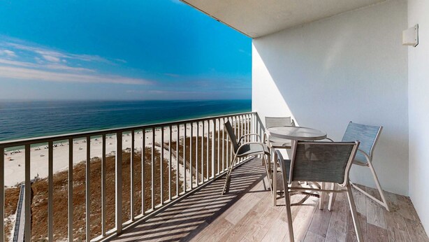 A balcony with a view of the ocean, a table, and two chairs. - Coastal condo w/ shared, outdoor pool, indoor pool w/ hot tub, & relaxing sauna (Orange Beach)