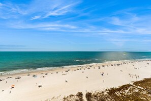 Ein Strand mit weitem Sandbereich, blauem Himmel und ruhigem Wasser.
