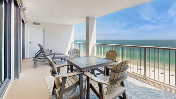 Un balcon avec une table et des chaises, une vue sur l’océan et une porte.