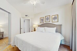 A hotel room with a bed, a ceiling fan, a door, and three framed pictures on the wall. - Stunning Gulf front condo w/ a spacious layout, shared pools, & fitness room (Orange Beach)