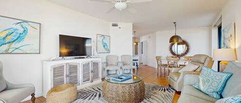 A living room with a ceiling fan, a television, a sofa, a coffee table, and a dining area with chairs.