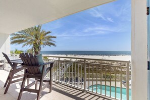 Ein Balkon mit Blick auf den Strand, einen Pool und Sitzgelegenheiten im Freien.
