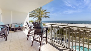 Een balkon met uitzicht op het strand, een bank en een stoel.