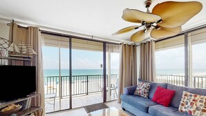Una sala de estar con sofá, televisión y vista a la playa.