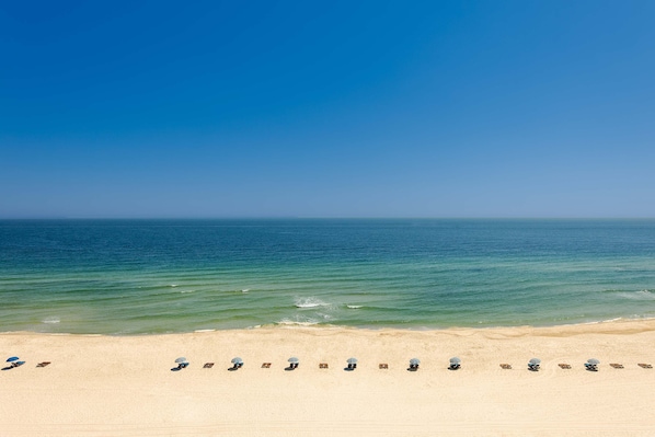 A beach with a row of sun loungers and umbrellas facing the ocean. - Beachfront condo with amazing views overlooking the Gulf of America featuring resort style pools. (Orange Beach)