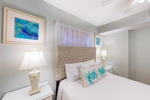 A bedroom with a bed, two bedside tables, a woven headboard, a framed picture on the wall, and a window with sheer curtains. - Serene water view condo with pools, sauna, tennis court, fitness center, W&D (Orange Beach)