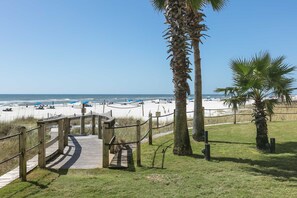 A wooden boardwalk leading to a beach with palm trees and a clear sky. - Gulf-front getaway with pool, hot tub, athletic courts & central AC (Orange Beach)