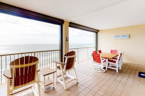 A balcony with a view of the ocean, wooden chairs, a table with red chairs, and a sign reading 'BEACH HOUSE'. - Gulf-front getaway with pool, hot tub, athletic courts & central AC (Orange Beach)