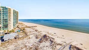 Ein Strandhotel mit mehreren Balkonen, einem Pool und einem Sandstrand.