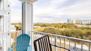 Ein Balkon mit zwei Stühlen, Blick auf einen Strand und Gebäude in der Ferne.