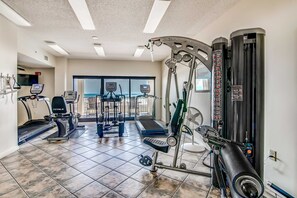 A gym with treadmills, elliptical machines, and weightlifting equipment. - Delightful Corner Getaway With Gulf Views, Beach Access, Free WiFi & Shared Pools (Orange Beach)