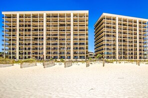 A beachfront hotel with multiple floors, balconies, and a sandy beach area. - Delightful Corner Getaway With Gulf Views, Beach Access, Free WiFi & Shared Pools (Orange Beach)
