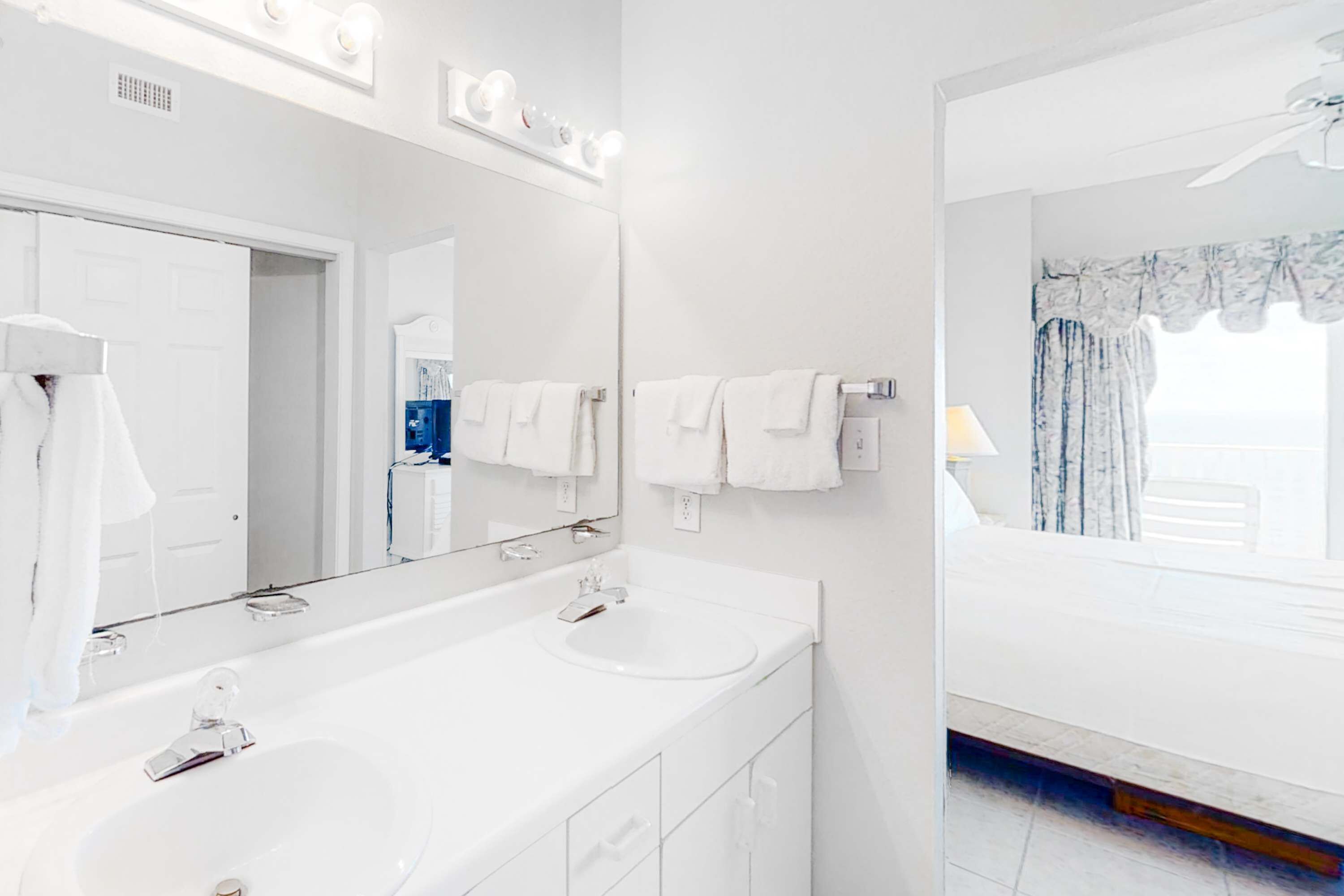 Une salle de bain moderne avec un grand miroir, deux lavabos et un espace douche.