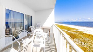 A balcony with white chairs and a table, overlooking a beach. - Beachfront Resort Condo Featuring Shared Hot Tub & Pool, Central AC, Free WiFi (Orange Beach)