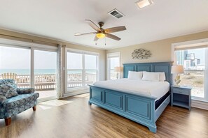 Ein Schlafzimmer mit einem großen Bett, einem Deckenventilator, einem Nachttisch und Blick auf den Ozean.