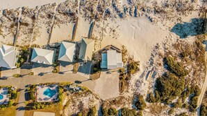 An aerial view of a resort with multiple buildings, a swimming pool, and a beach.