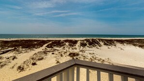 A beach view with a wooden deck and sandy dunes.