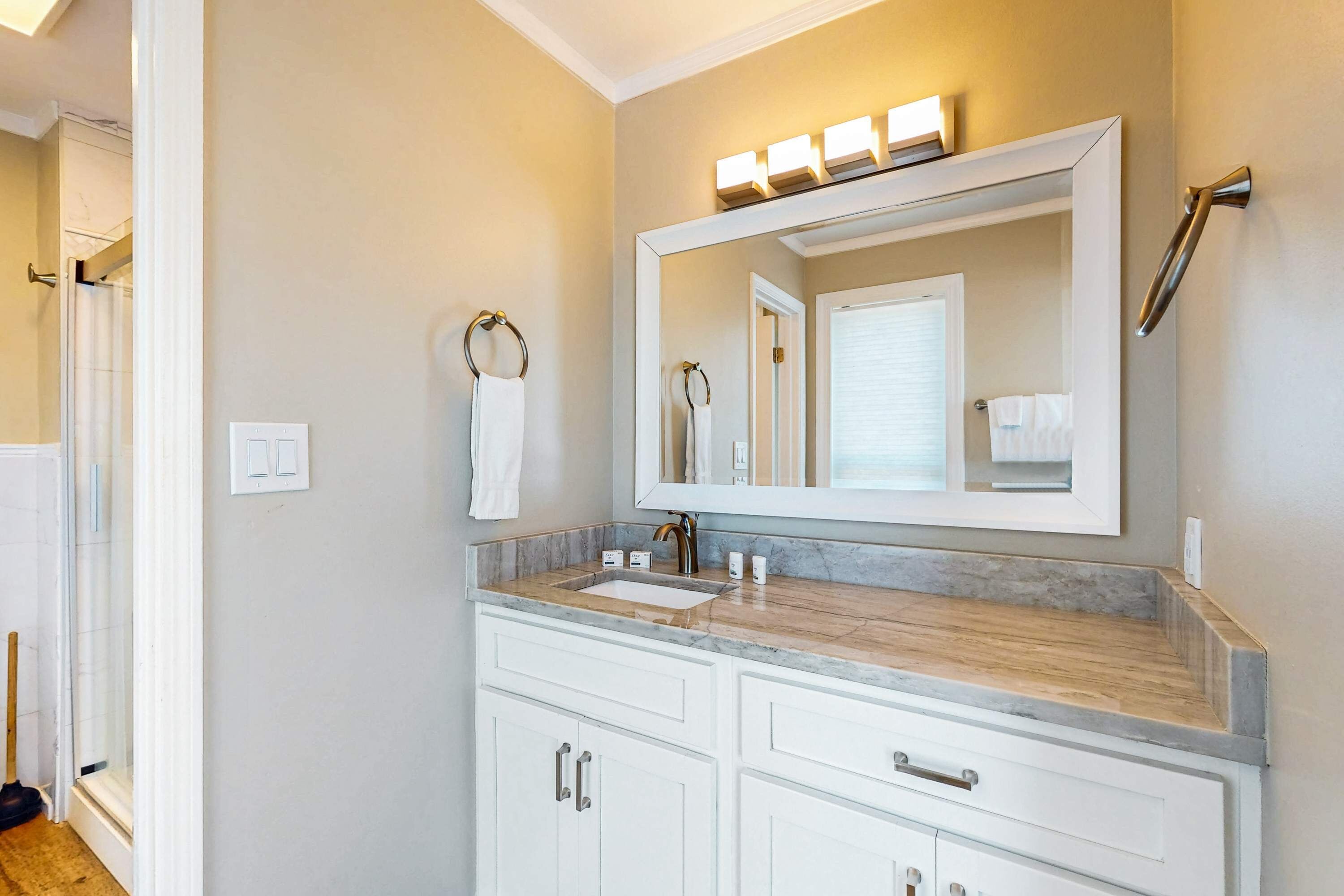 A bathroom with a large mirror, a sink, and a shower.
