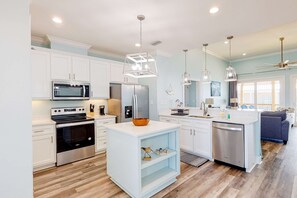 A modern kitchen with white cabinetry, stainless steel appliances, and pendant lighting.