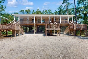 A two-story wooden structure with a covered deck and multiple staircases. - Modern island gem with perfect location, WiFi, central AC, full kitchen & W/D (Dauphin Island)
