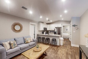 A modern kitchen with white cabinets, a central island, and bar stools. - Modern island gem with perfect location, WiFi, central AC, full kitchen & W/D (Dauphin Island)