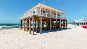 Una casa frente a la playa con balcón, terraza de madera y vista al océano.