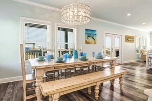 A dining area with a wooden table, bench, and pendant light. - Waterfront home with private grill, dock, and washer & dryer (Dauphin Island)