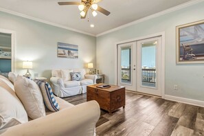 A living room with a sofa, a wooden coffee table, and a ceiling fan. - Waterfront home with private grill, dock, and washer & dryer (Dauphin Island)