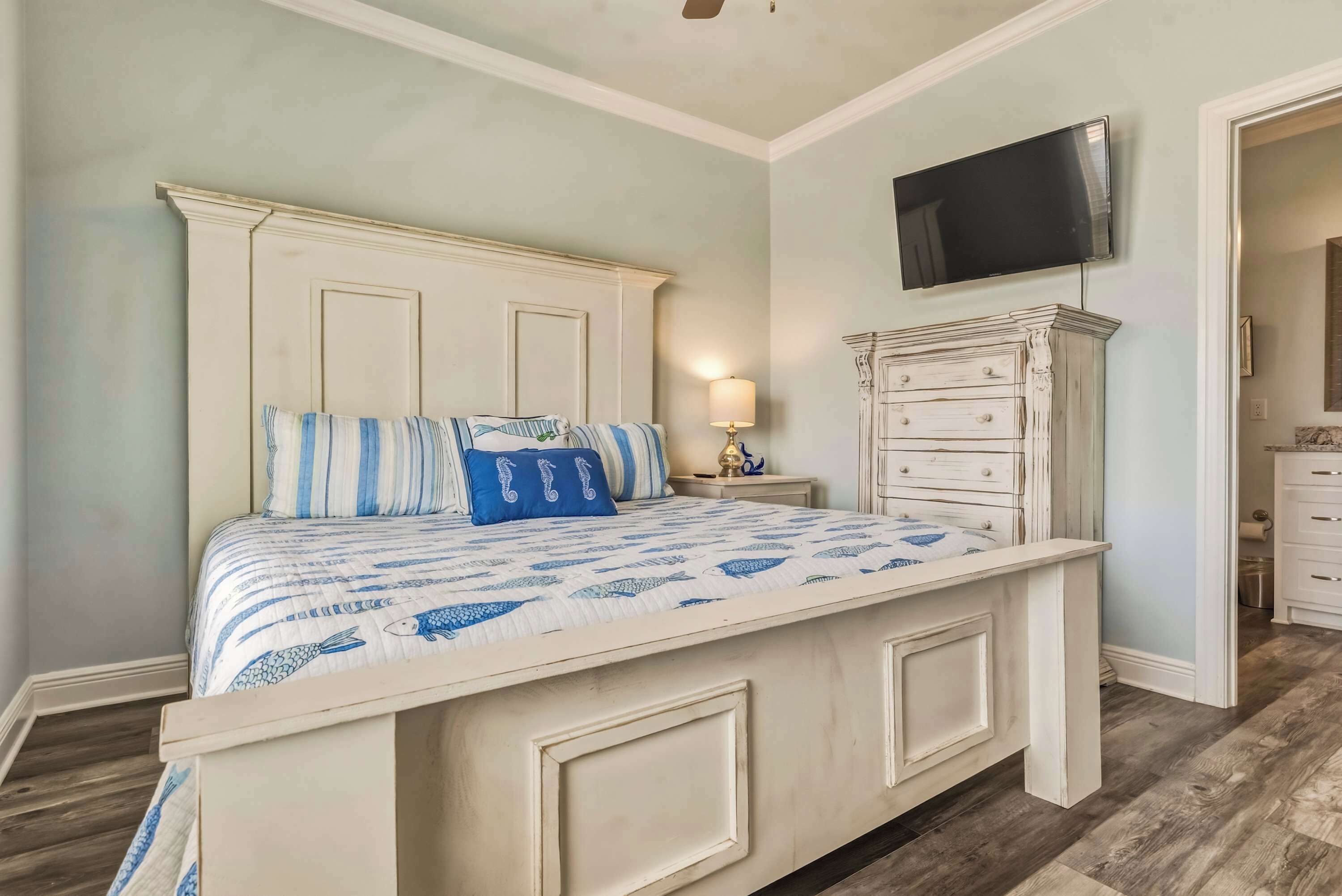 Un dormitorio con una cama, televisión montada en la pared y un aparador.