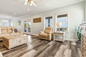 A spacious living room with a beige sofa, a leather armchair, a wooden coffee table, and a fireplace. - Waterfront home with private grill, dock, and washer & dryer (Dauphin Island)
