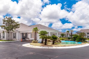 A residential area with houses, a swimming pool, and palm trees.