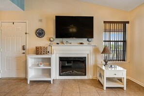A living room with a fireplace, a television, and a window with bars.