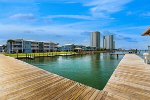 Ein Hotel am Wasser mit einer Holzterrasse, einem Pool und modernen Gebäuden im Hintergrund.