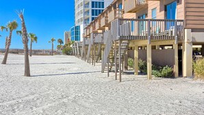 Een strandhotel met meerdere balkons, een zandstrand en palmbomen.
