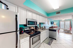A compact kitchen with white cabinets, a stainless steel refrigerator, a microwave, an oven, and a dishwasher. - Gulf-front condo with central AC, balcony & pool (Gulf Shores)