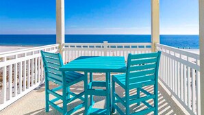 Ein überdachter Außenbereich mit Tisch und Stühlen mit Blick auf einen Strand und den Ozean.
