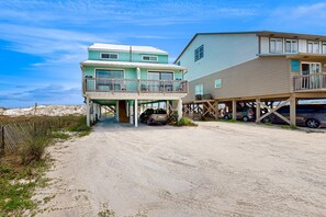 A beachfront property with a two-story house, a covered porch, and a carport. - Bright and Attractive Home Overlooking the Water w/Free WiFi & Central AC (Gulf Shores)