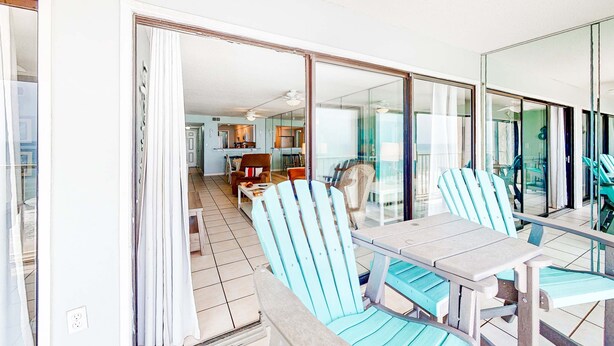 A room with a dining table, chairs, and a view through a glass door to a kitchen and living area. - 8th-floor beachfront condo with Gulf view, waterfront pool, & balcony (Gulf Shores)