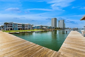 Ein Hotel am Wasser mit einer Holzterrasse, einem Pool und modernen Gebäuden im Hintergrund.