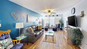 Ein Wohnzimmer mit blauer Wand, einem Ledersofa, einem Couchtisch und einem Fernseher.