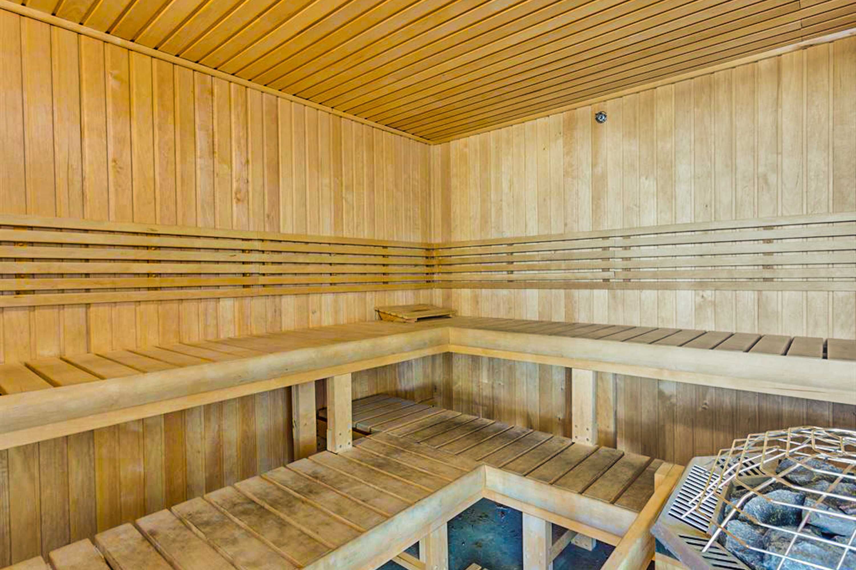 Un sauna avec des bancs en bois et un porte-serviettes en métal.